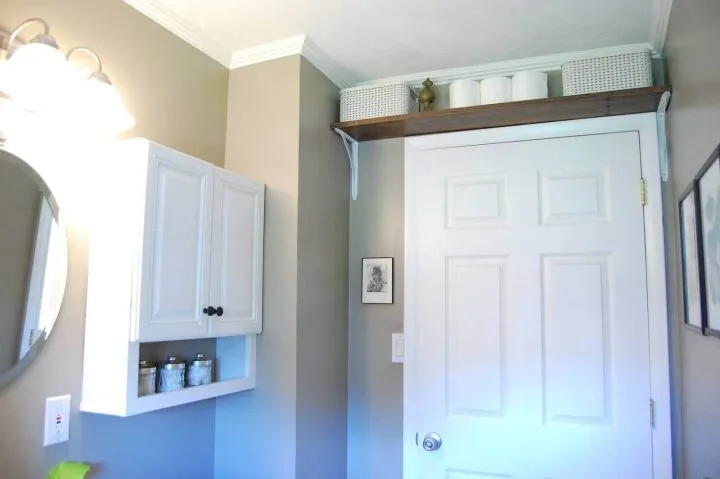 Компактная антресоль или полка удачно займёт свободное пространство над дверью в ванной